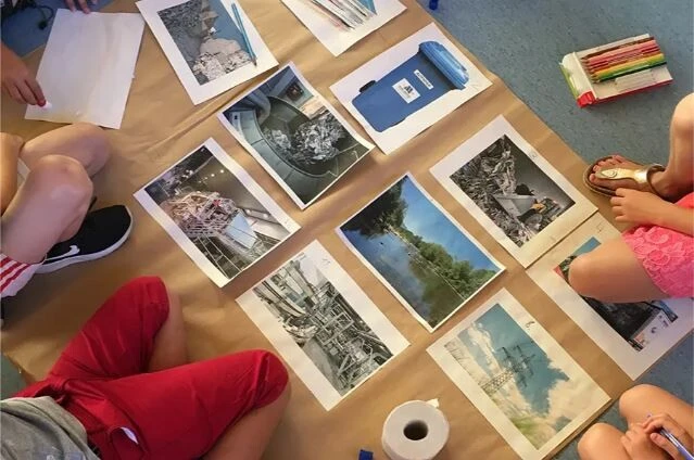Kinder sitzen im Kreis um ausgelegte Bildkarten und betrachten gemeinsam verscheidene Motive.