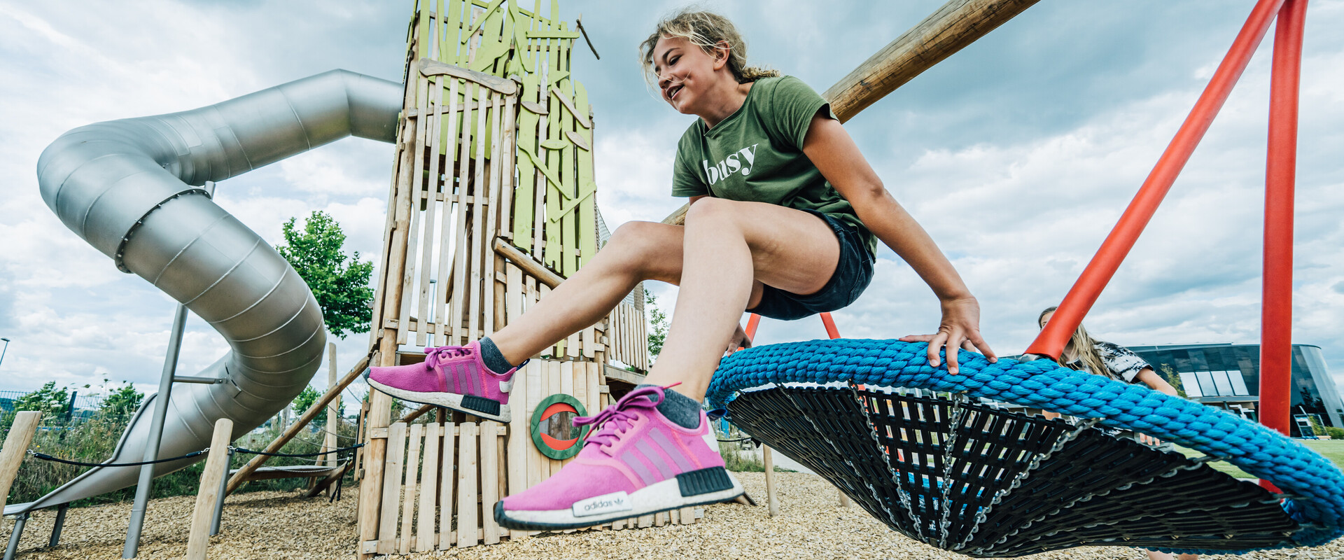 M&auml;dchen springt von Schaukel auf Spielplatz.